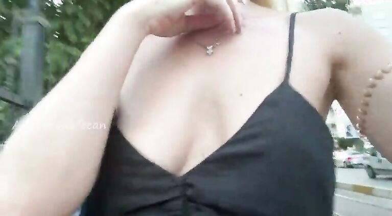 A hot girl walks around the city in a loose dress without underwear, shines her breasts in a public place.